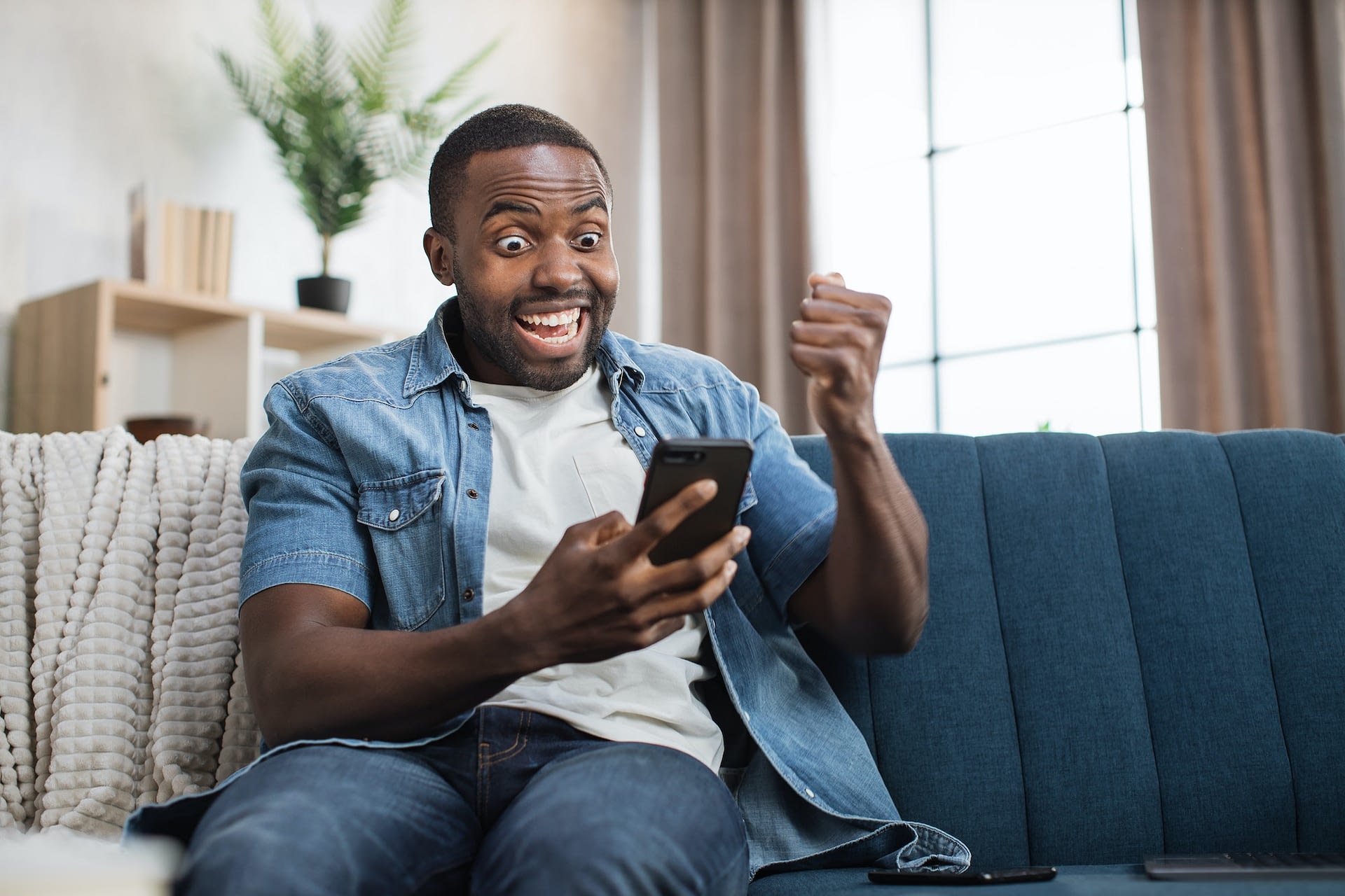 african guy gesturing from happiness while looking on mobile