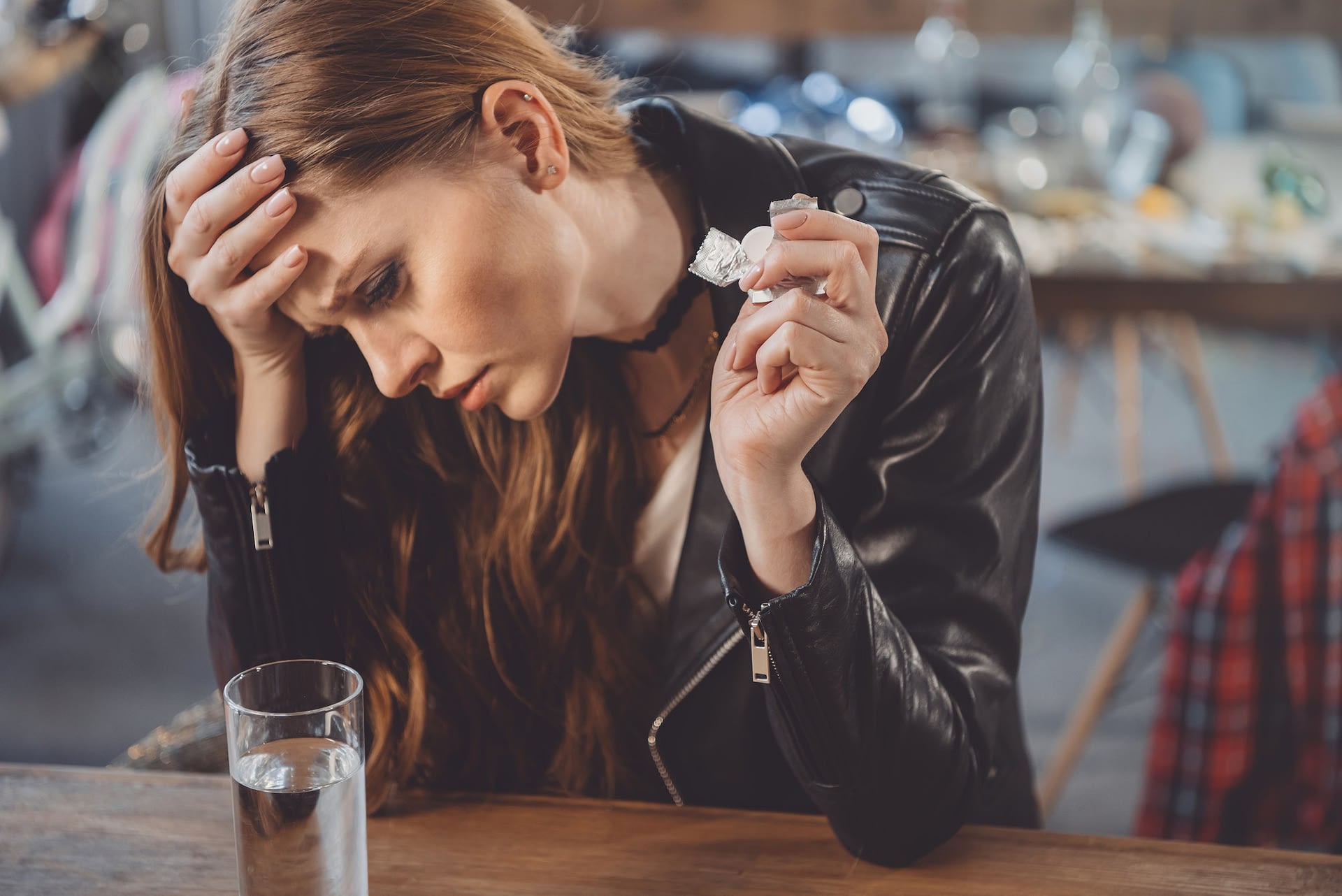 attractive woman with hangover with medicines after party at home