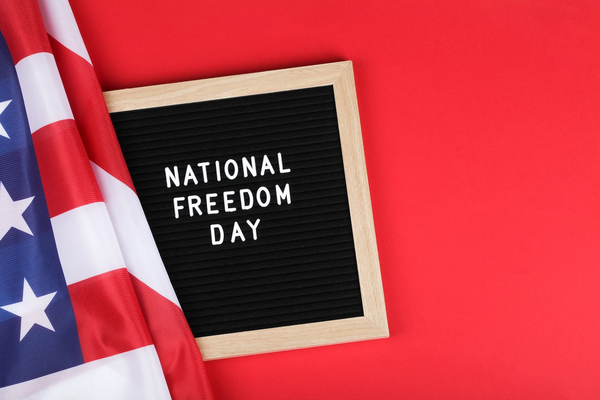 black letter board with text national freedom day and american flag on red background top view