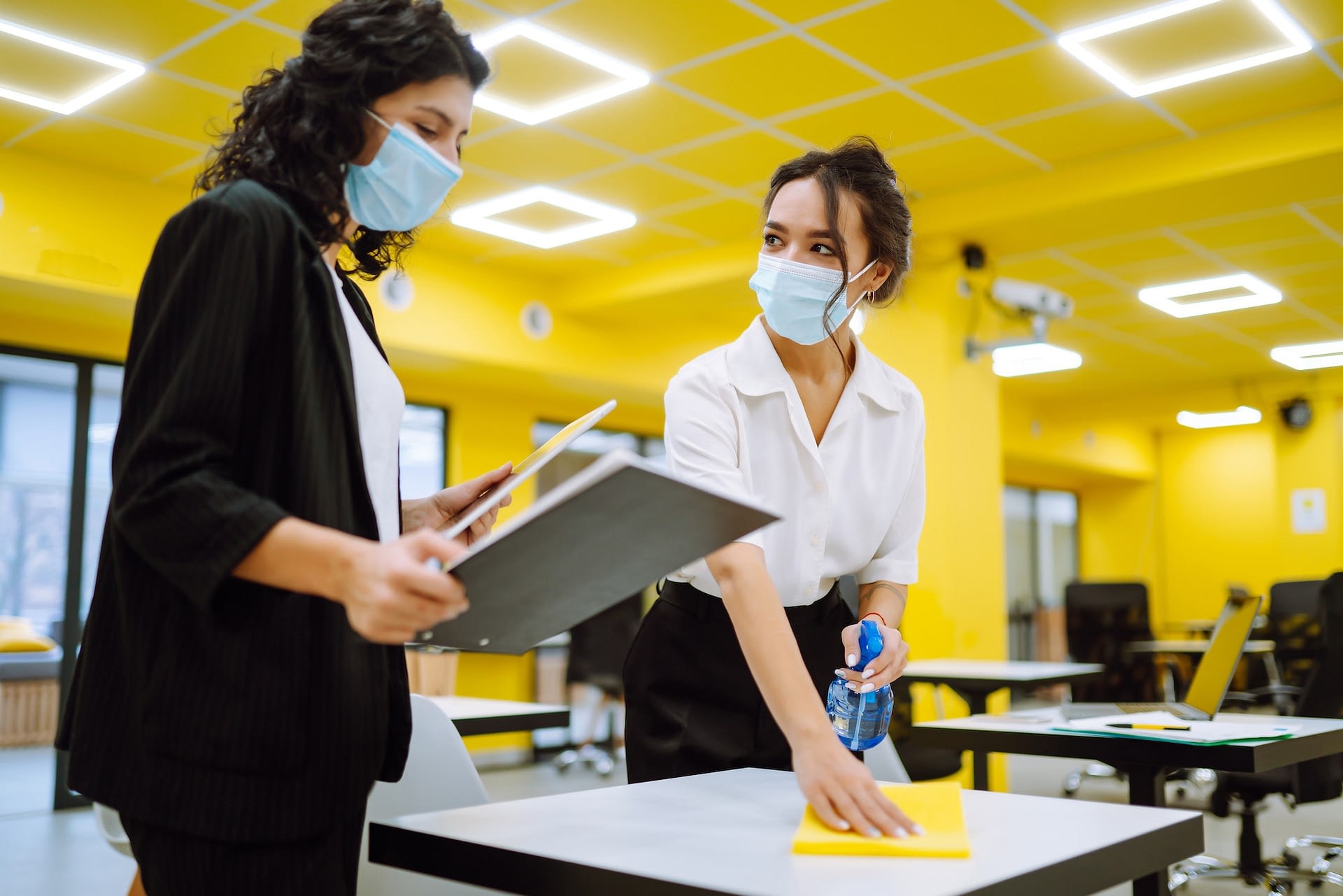 cleaning and disinfection of the desktop man in protective sterile mask cleans the working desk