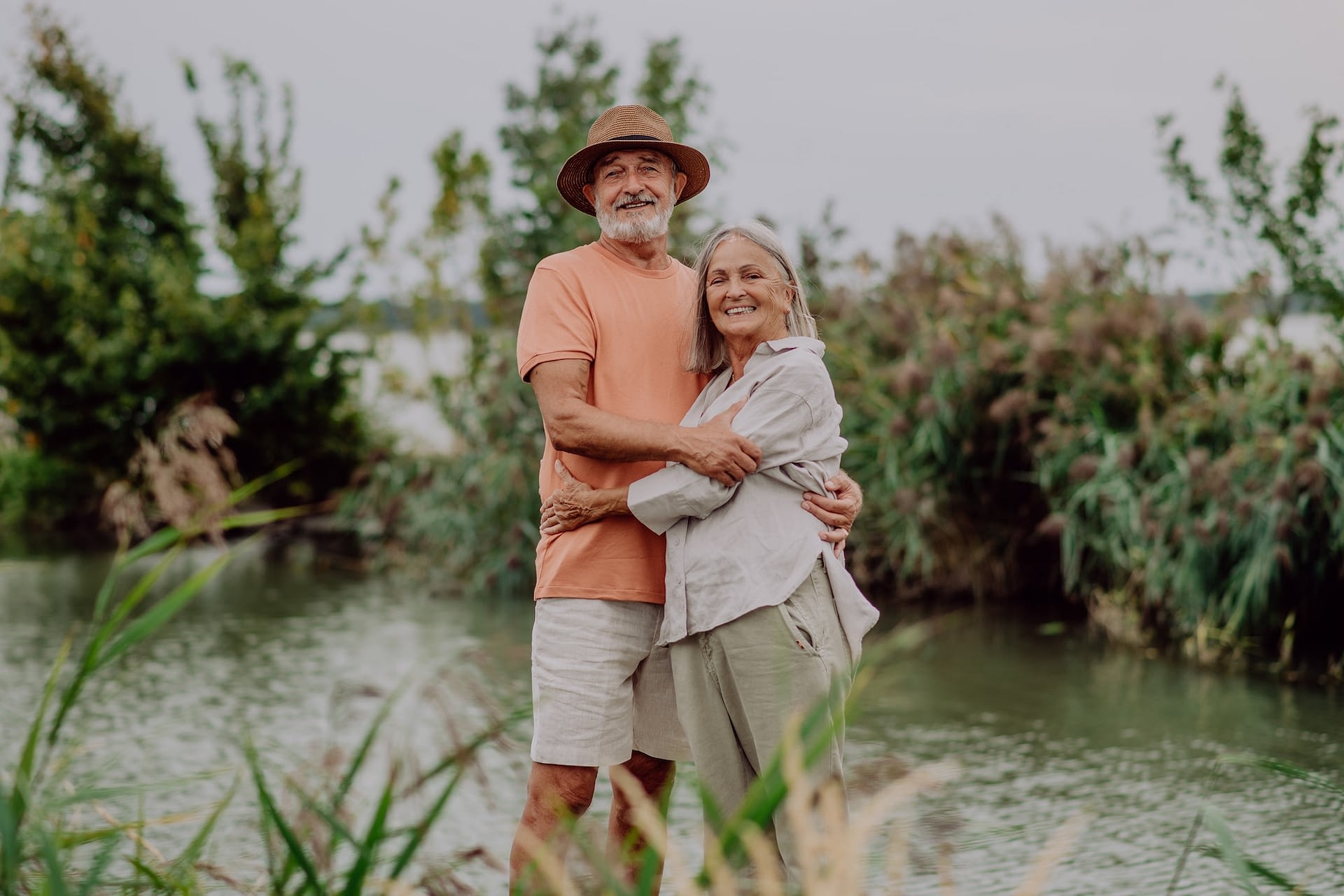 happy senior couple hugging on walk near the lake during autumn day