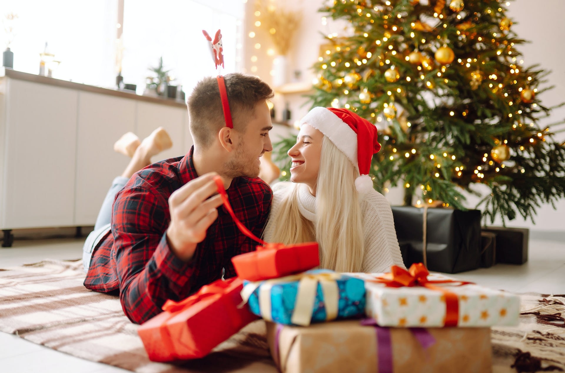 young couple with christmas gifts at home near christmas tree romantic day holidays new years 