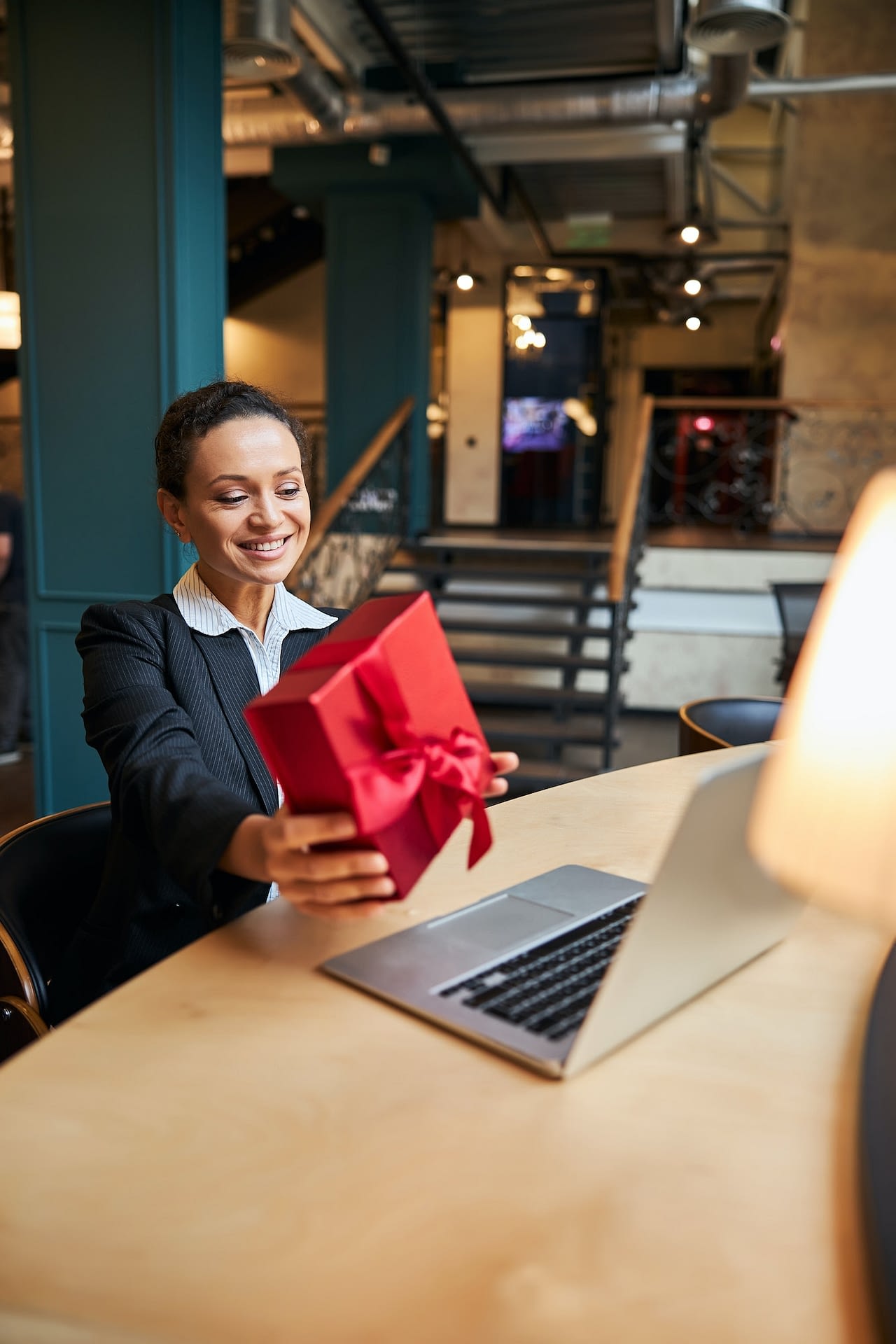 pleased brunette office worker demonstrating gift box