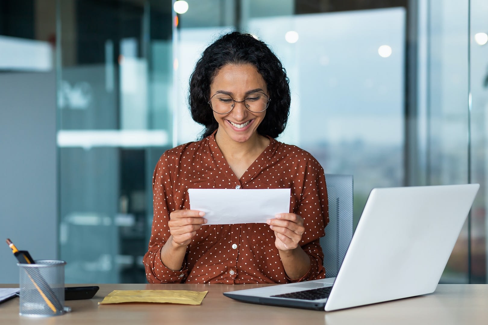 businesswoman received happy news letter from bank hispanic woman with curly hair and glasses works