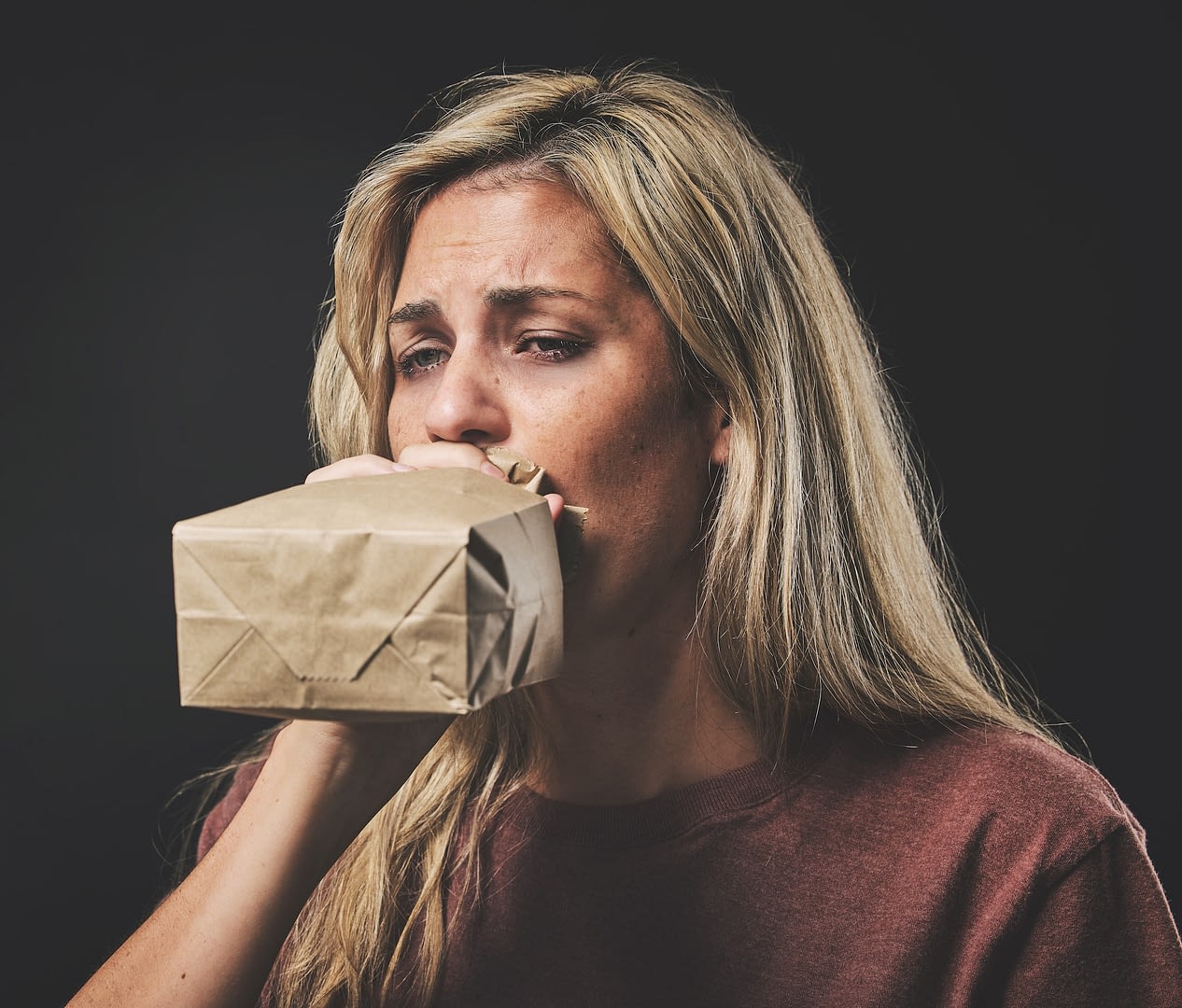 anxiety scared woman breathing into paper bag on dark background for mental health or psychology m