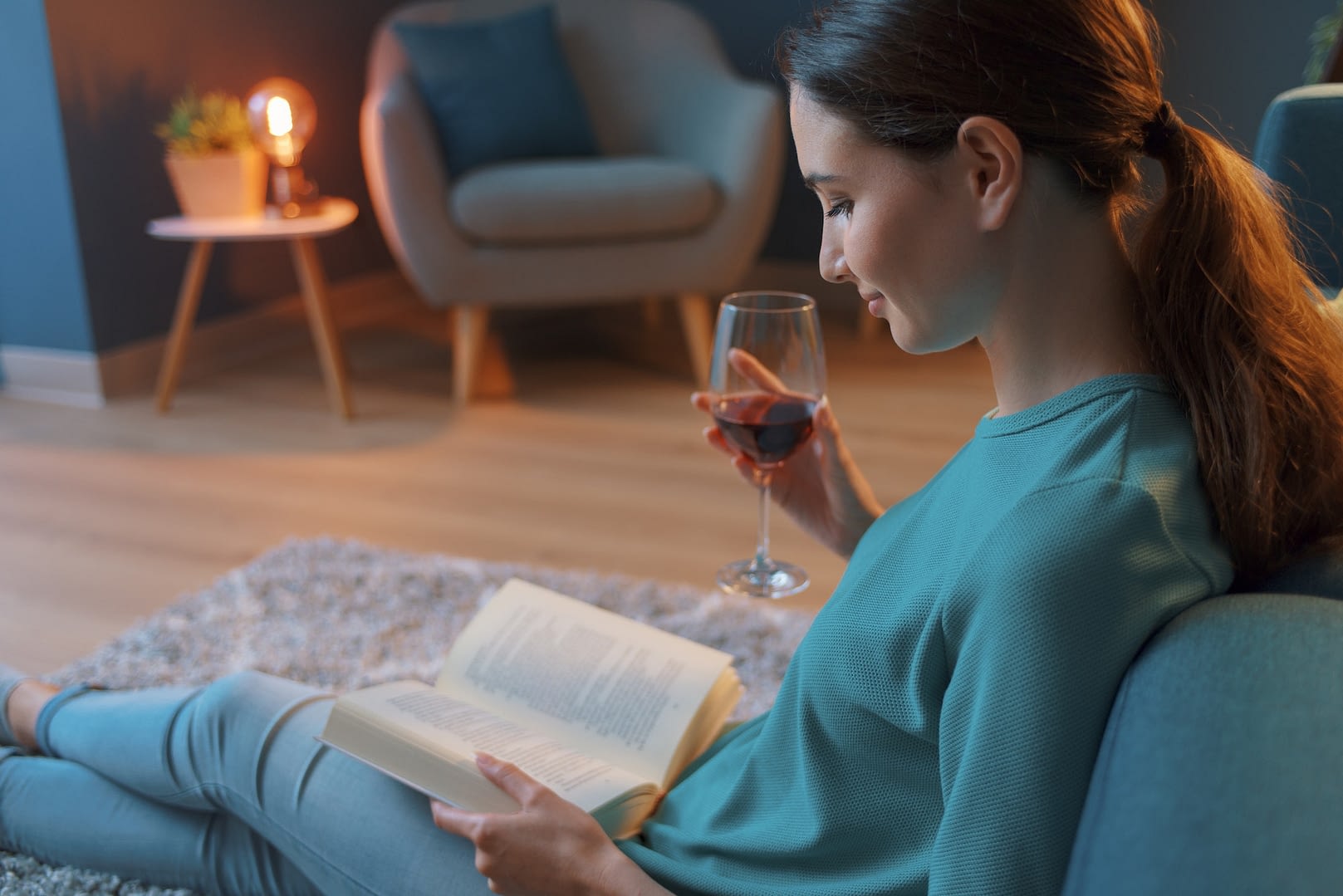 woman reading a book and drinking wine