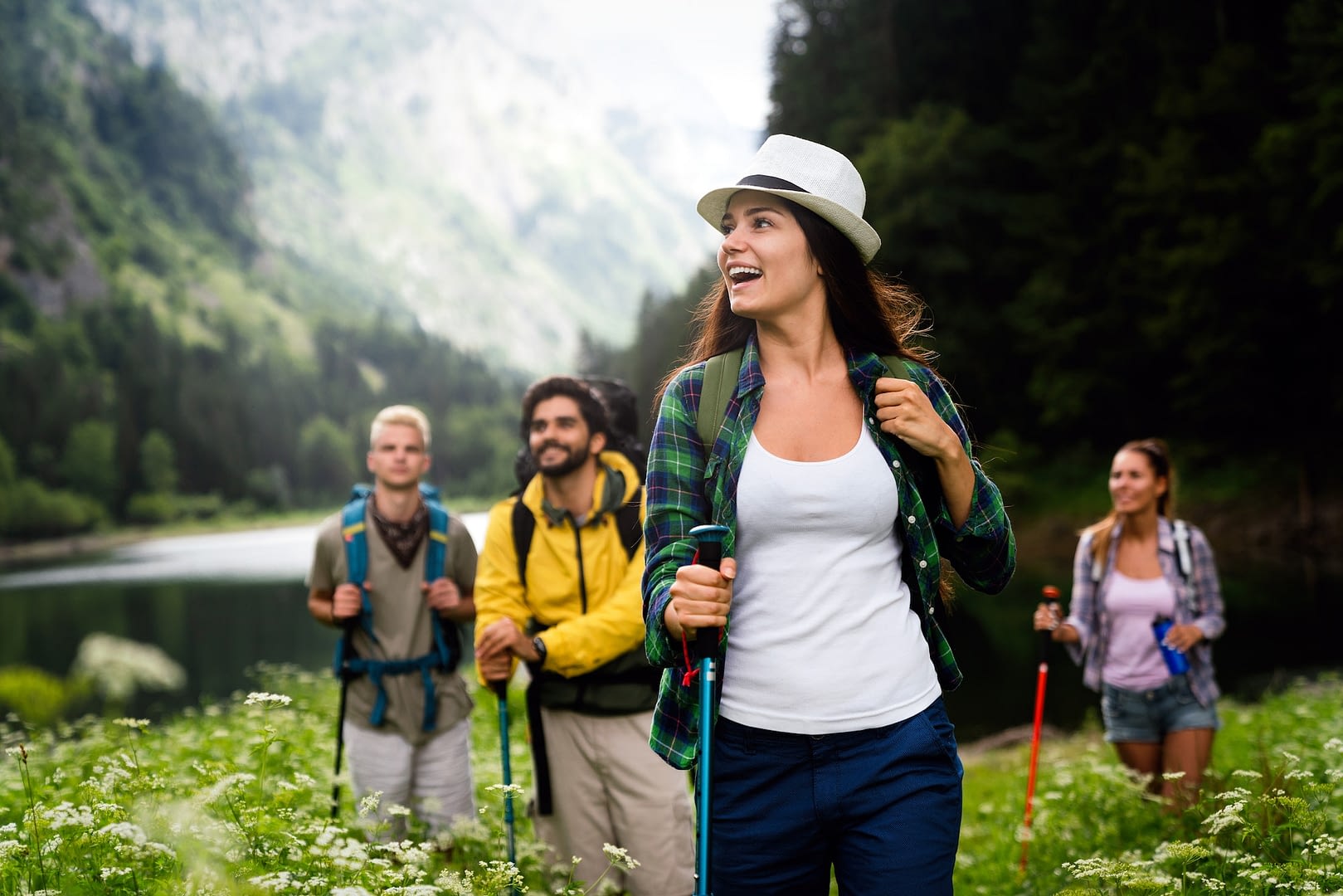 group of smiling friends hiking with backpacks outdoors travel tourism hike and people concept