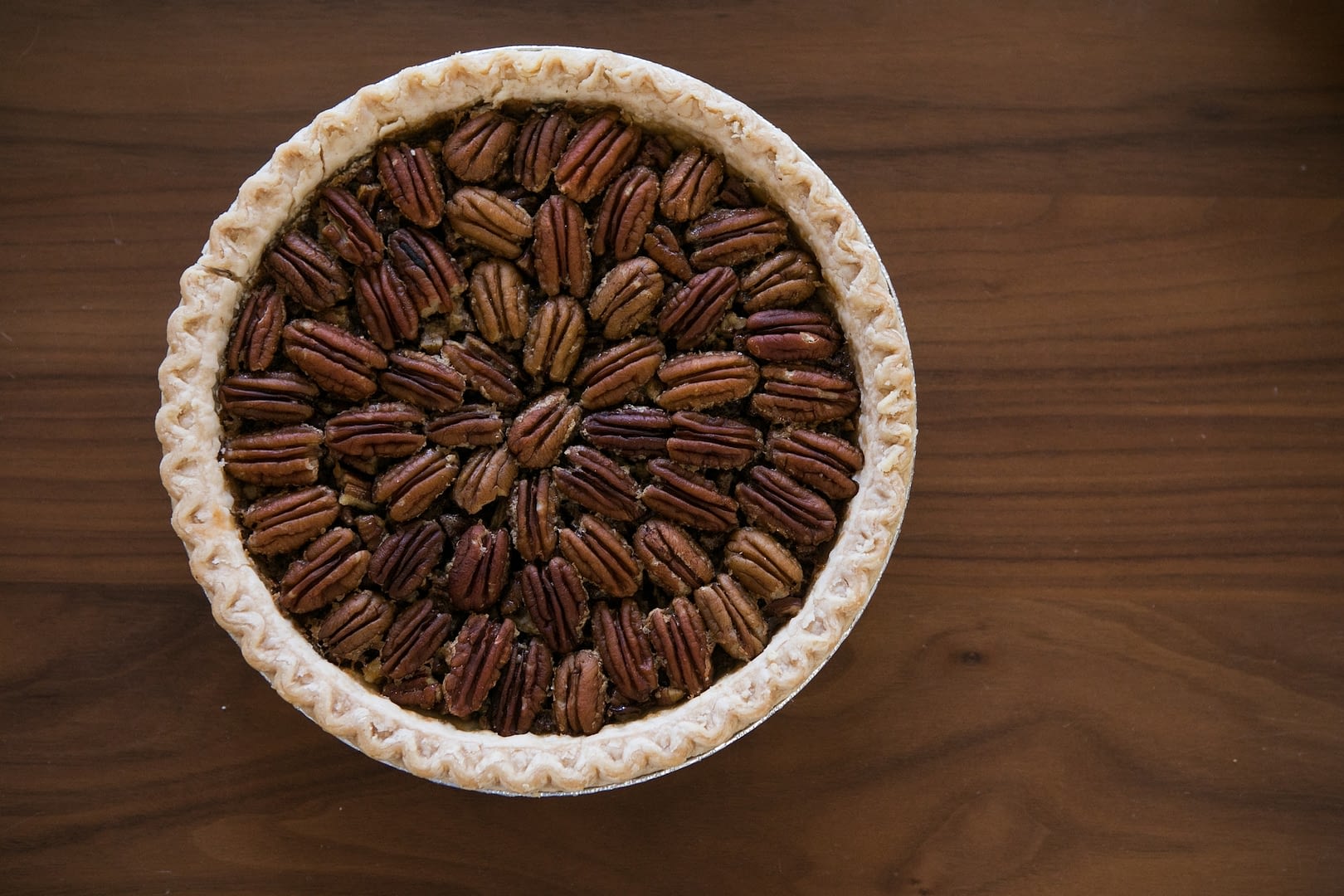 a pecan pie on cutting board with ingredients including pecans and eggs