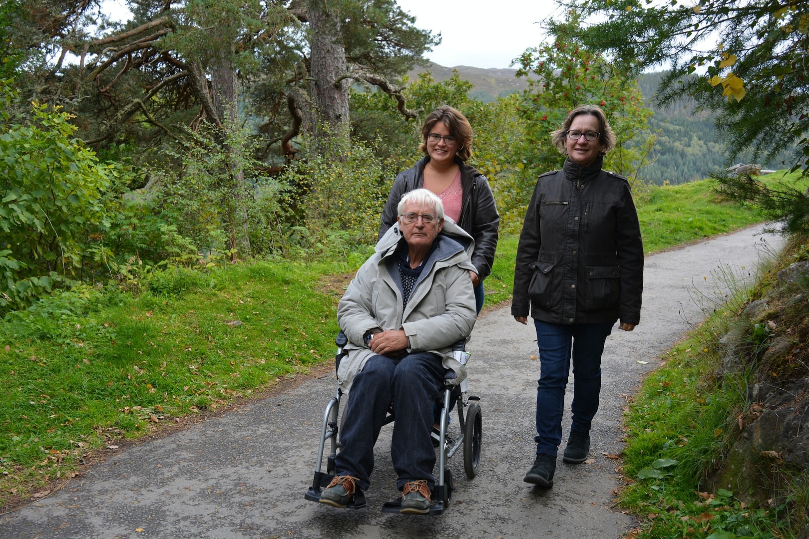 acts of support and kindness family going for a walk with senior man in a wheelchair