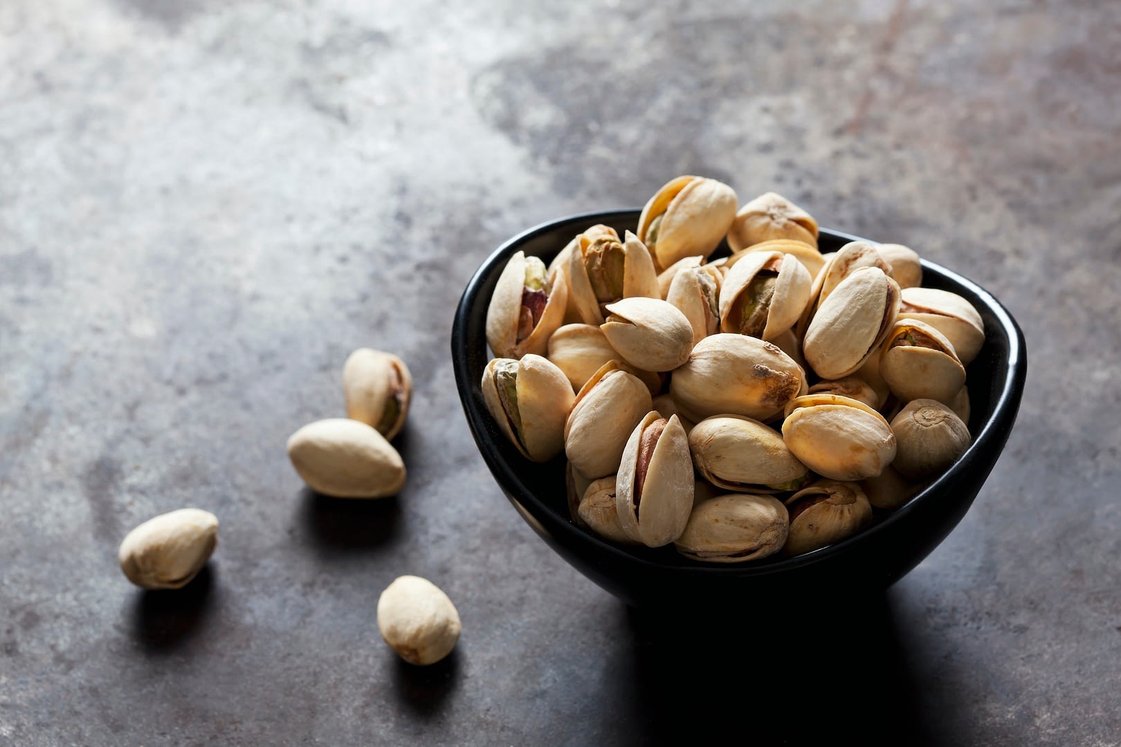 bowl of roasted and salted pistachios on slate