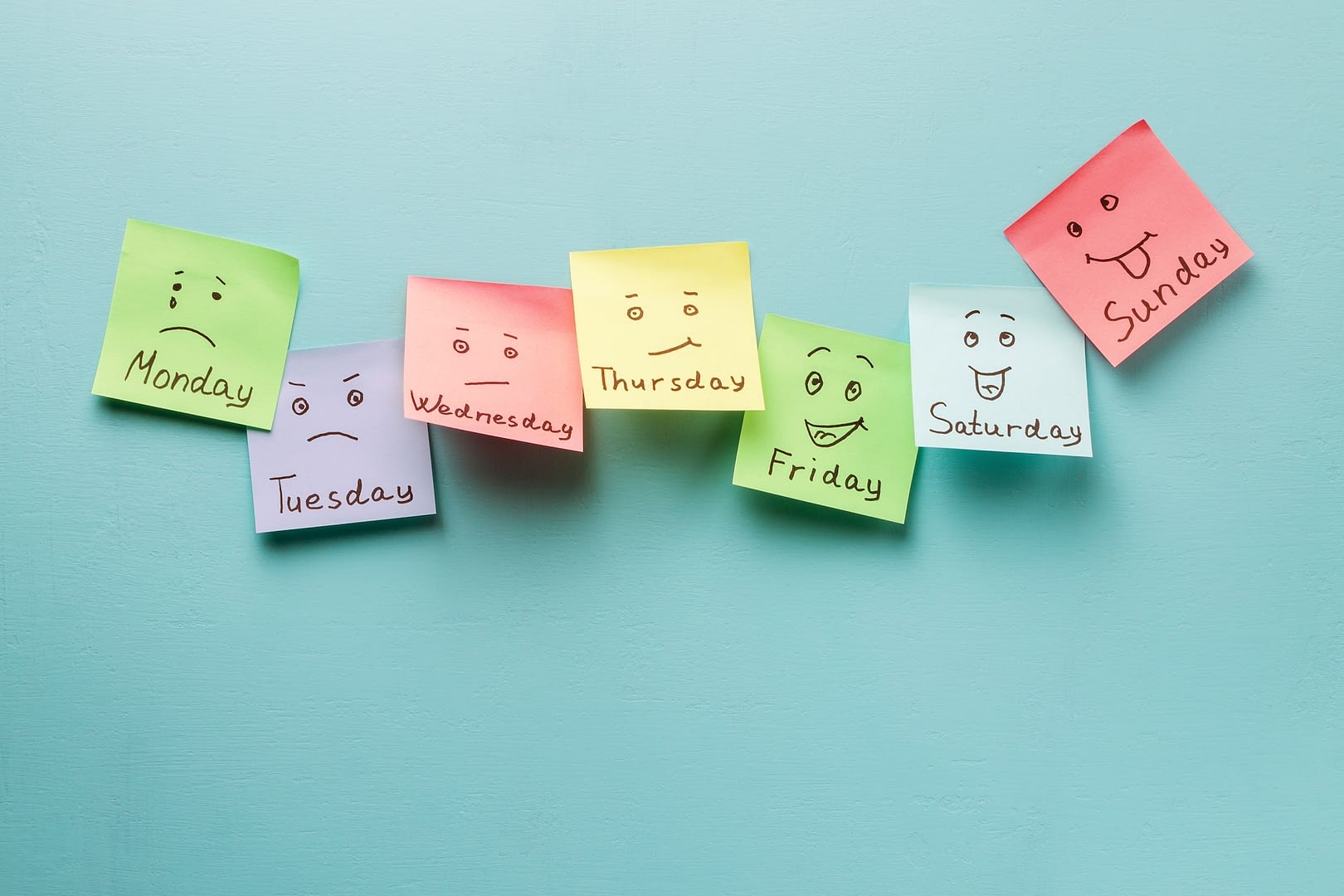 day of week and face expression colored stickers on a blue background