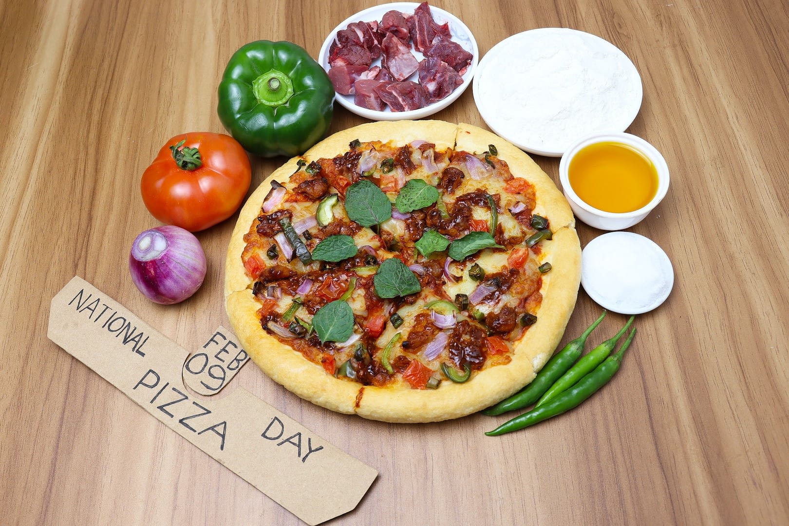 delicious sliced pizza with raw ingredients and a national pizza day sign on a table