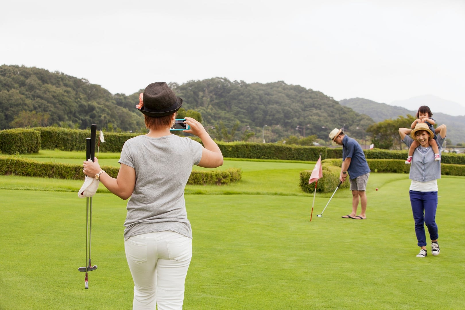 family on a golf course a child and three adults a woman with a camera