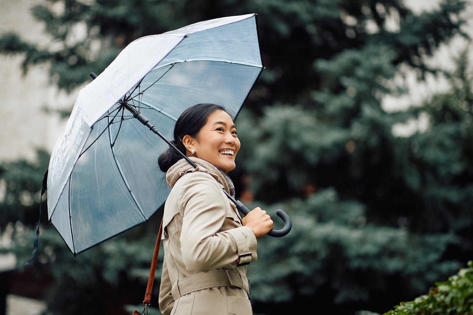 happy asian businesswoman with umbrella taking a walk during a rainy day