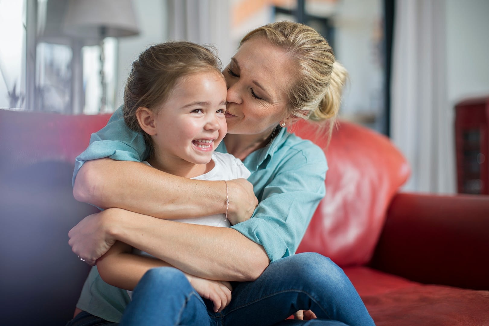 mother and daughter on sofa cuddling and smiling
