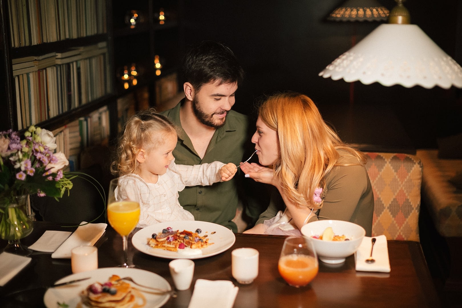 parents with their curly daughter having healthy meal together nutrition concept