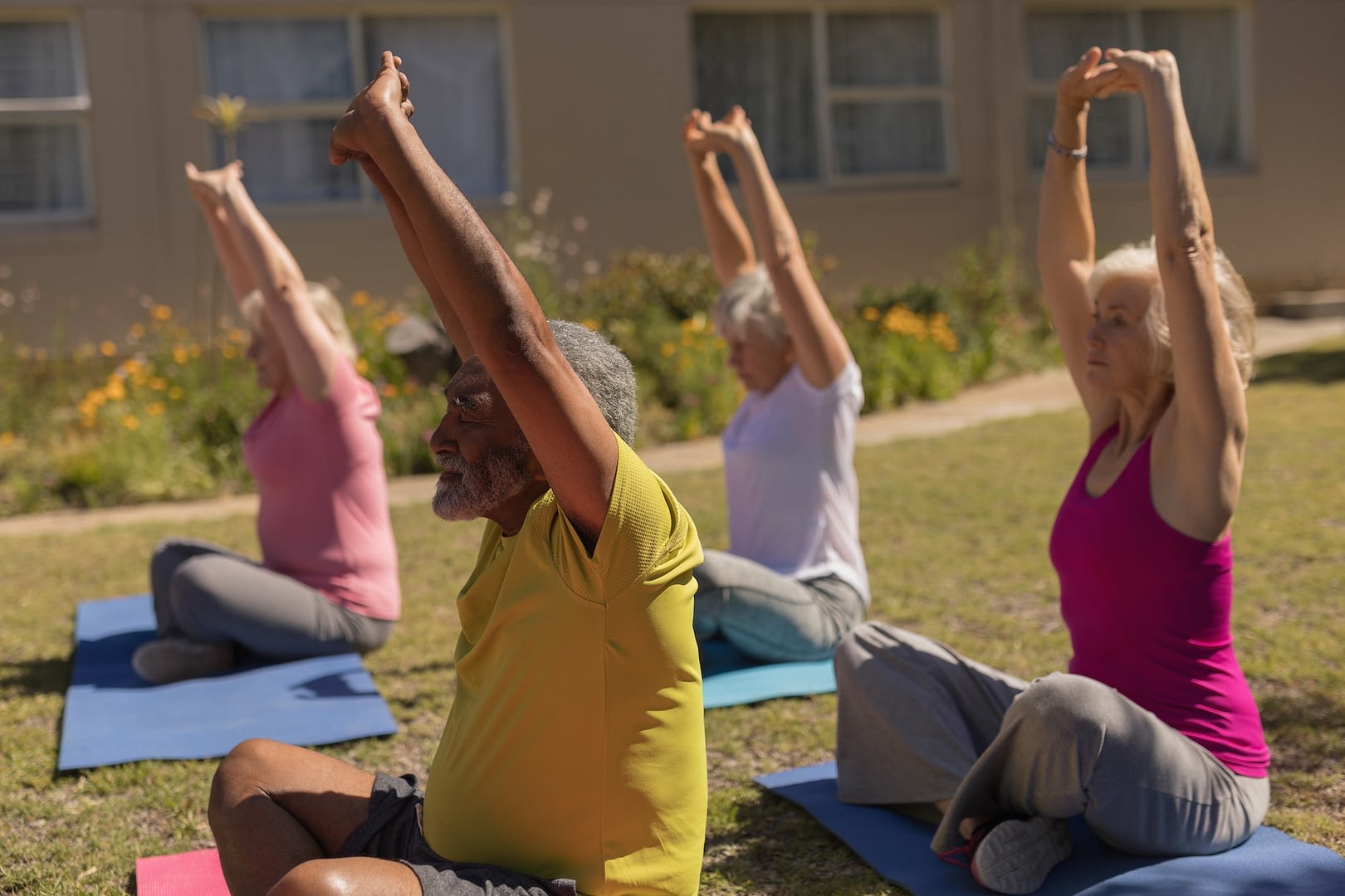 side view of active senior people performing yoga on yoga mat in the park