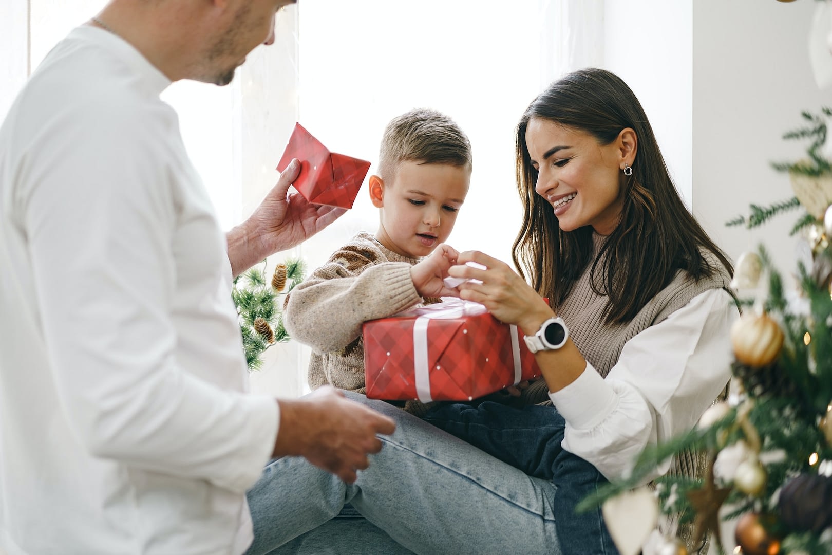 smiling parents giving christmas present to son at home