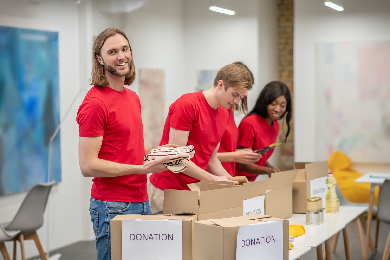 young peeple in red packing the cardboards with humanitarian help