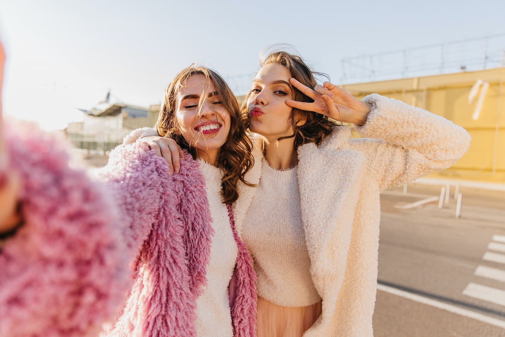 emotional girls posing in autumn day outdoor shot of best friends making selfie on the street