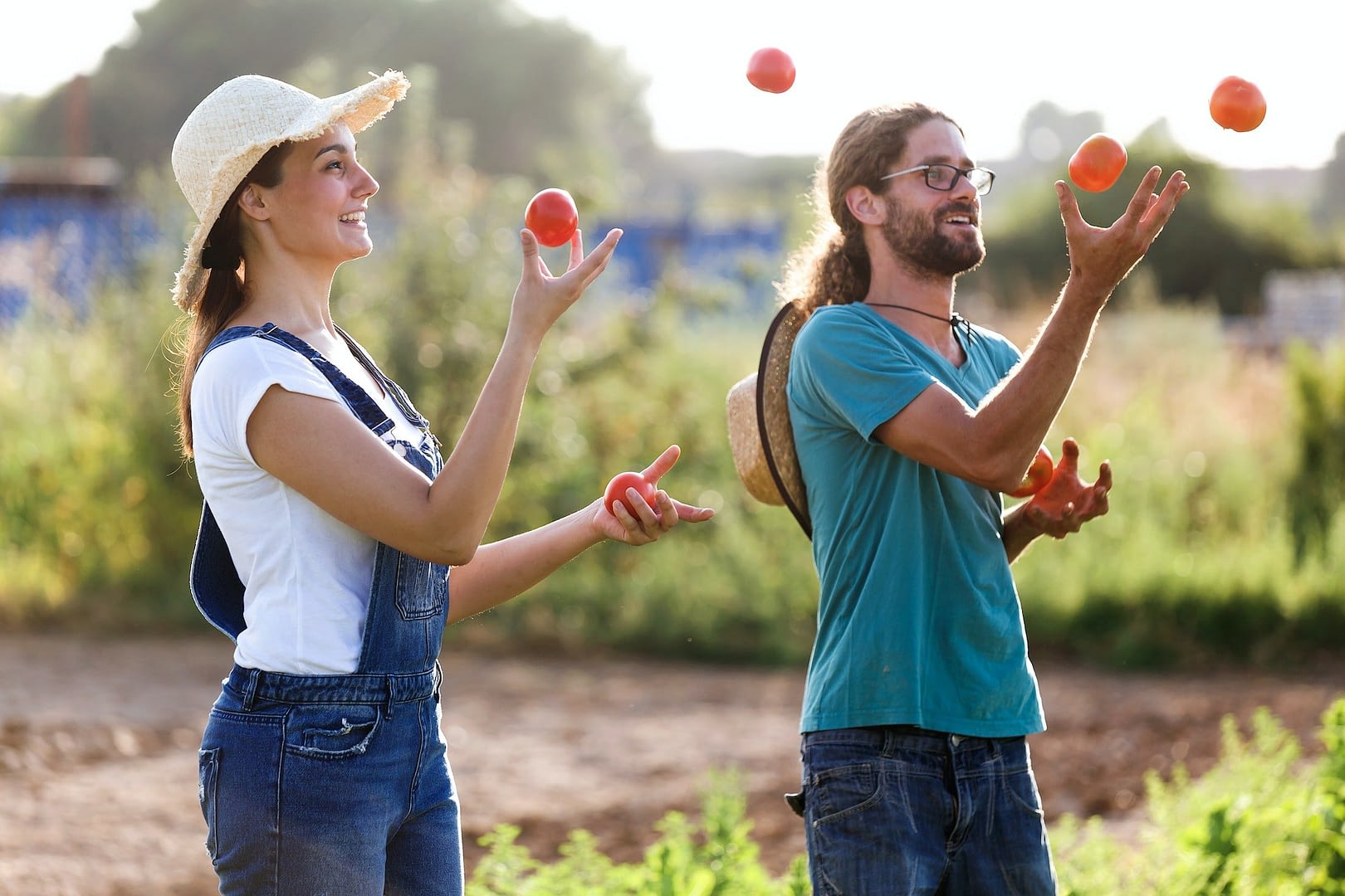 funny horticulturist couple juggling with fresh tomatoes in the