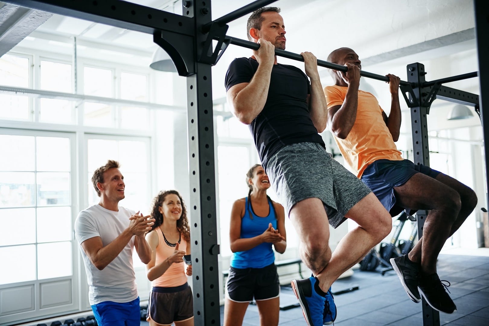 people watching two men doing pullups in a health club