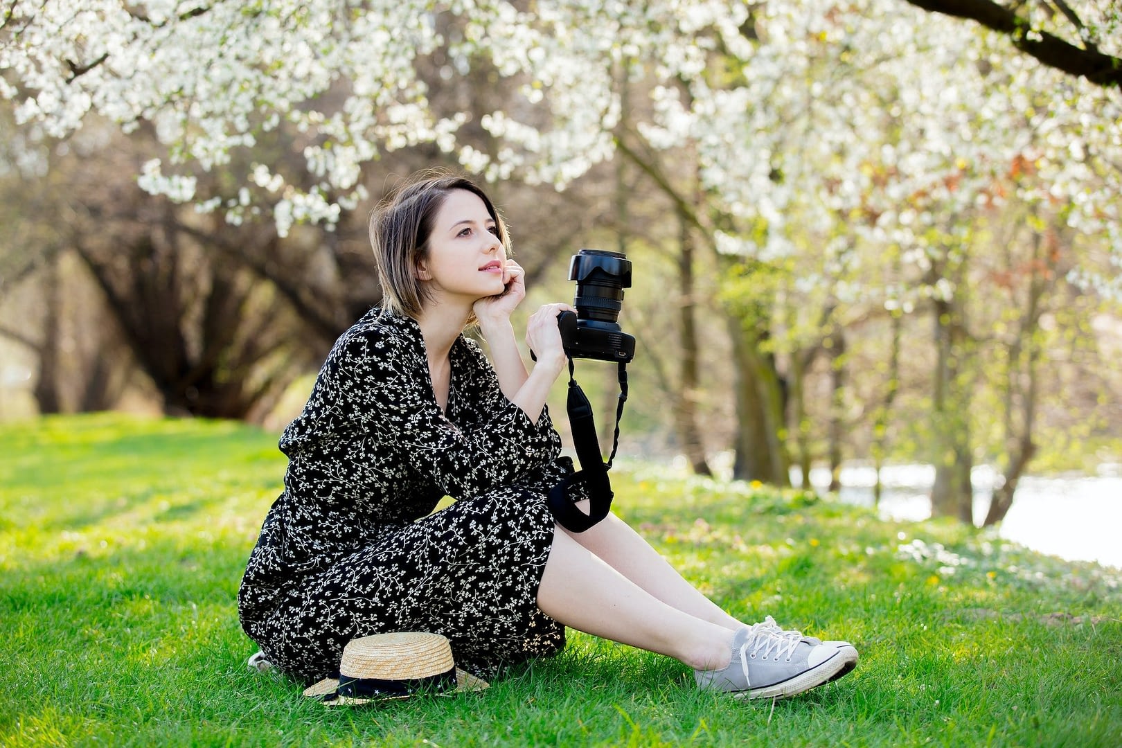 young girl with camera sitting near a flowering tree i