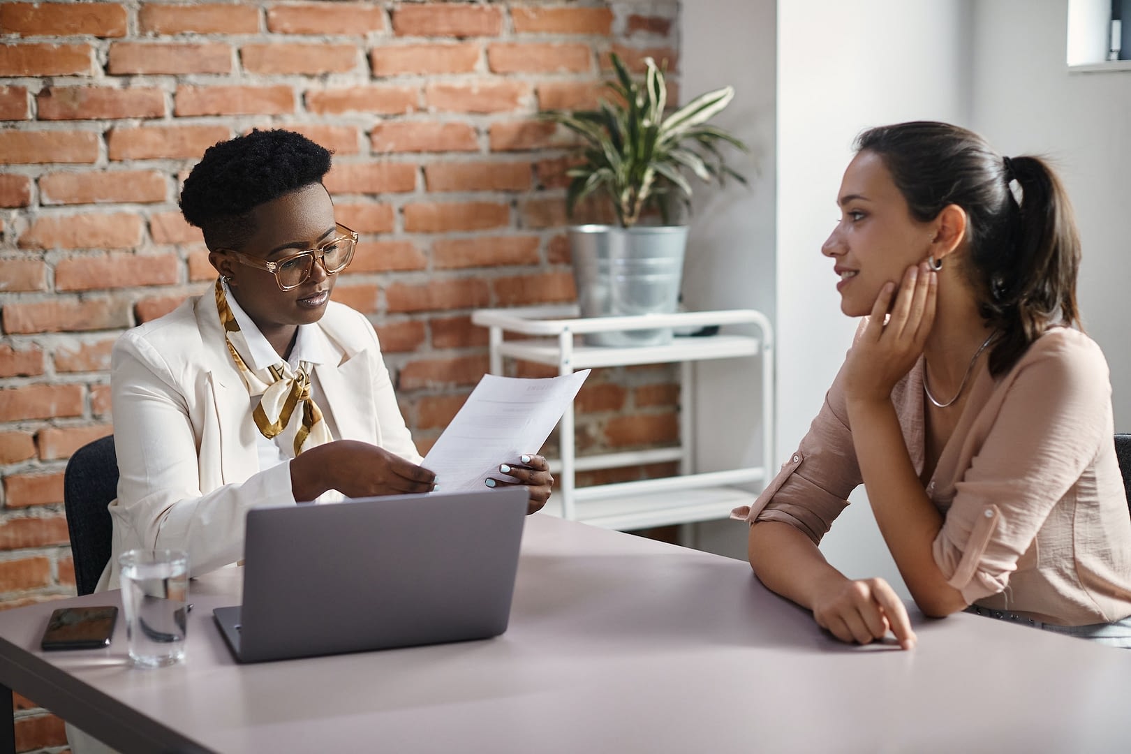 black businesswoman reading resume of female candidate during job interview in the office
