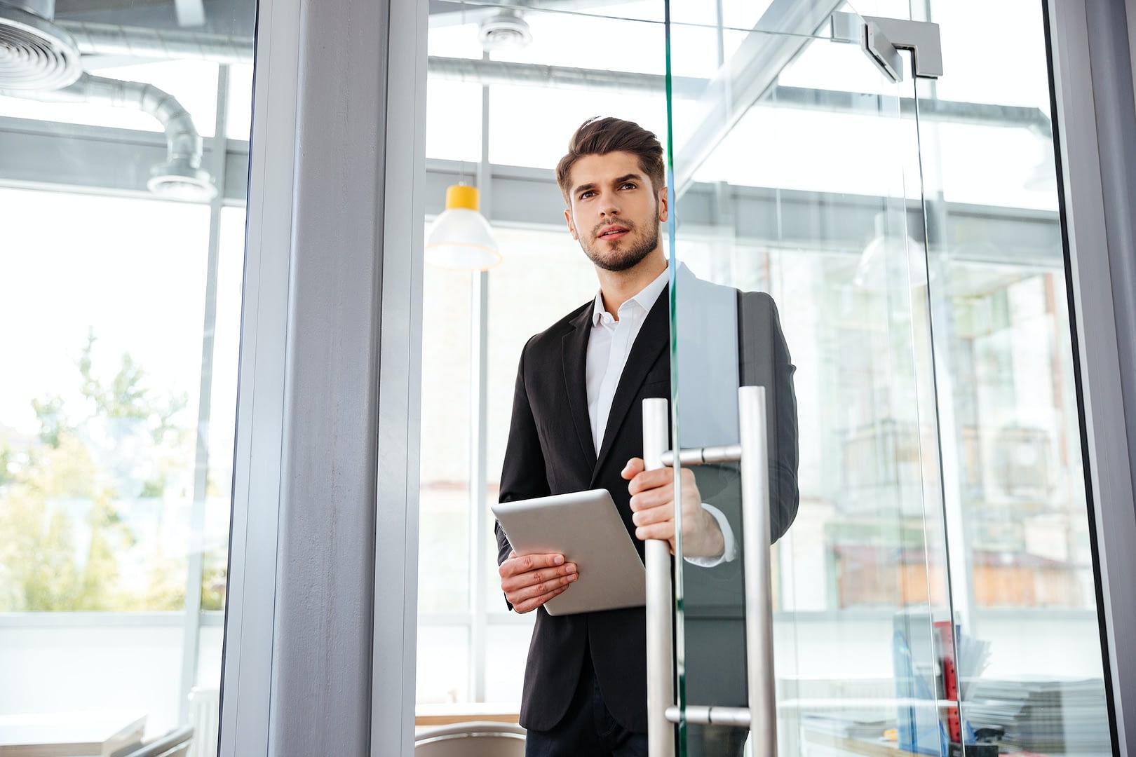 businesman with tablet entering the door in office