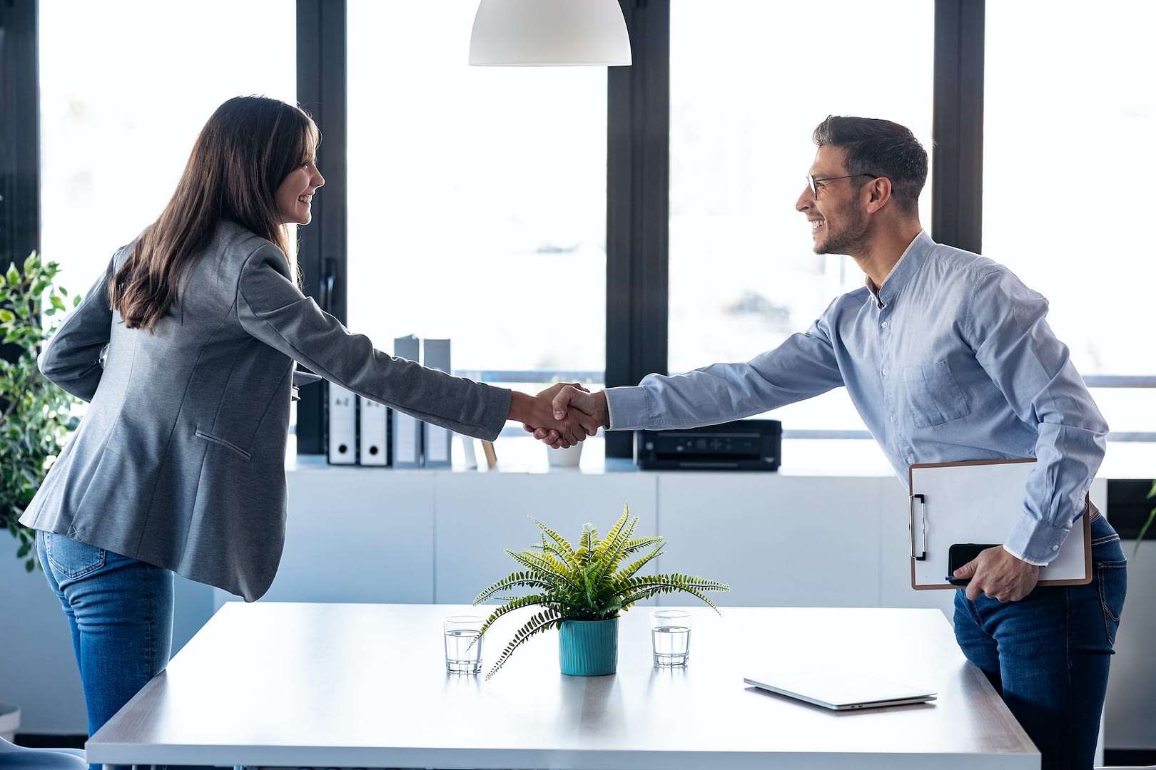 business people shaking their hands while smiling after signing new contract
