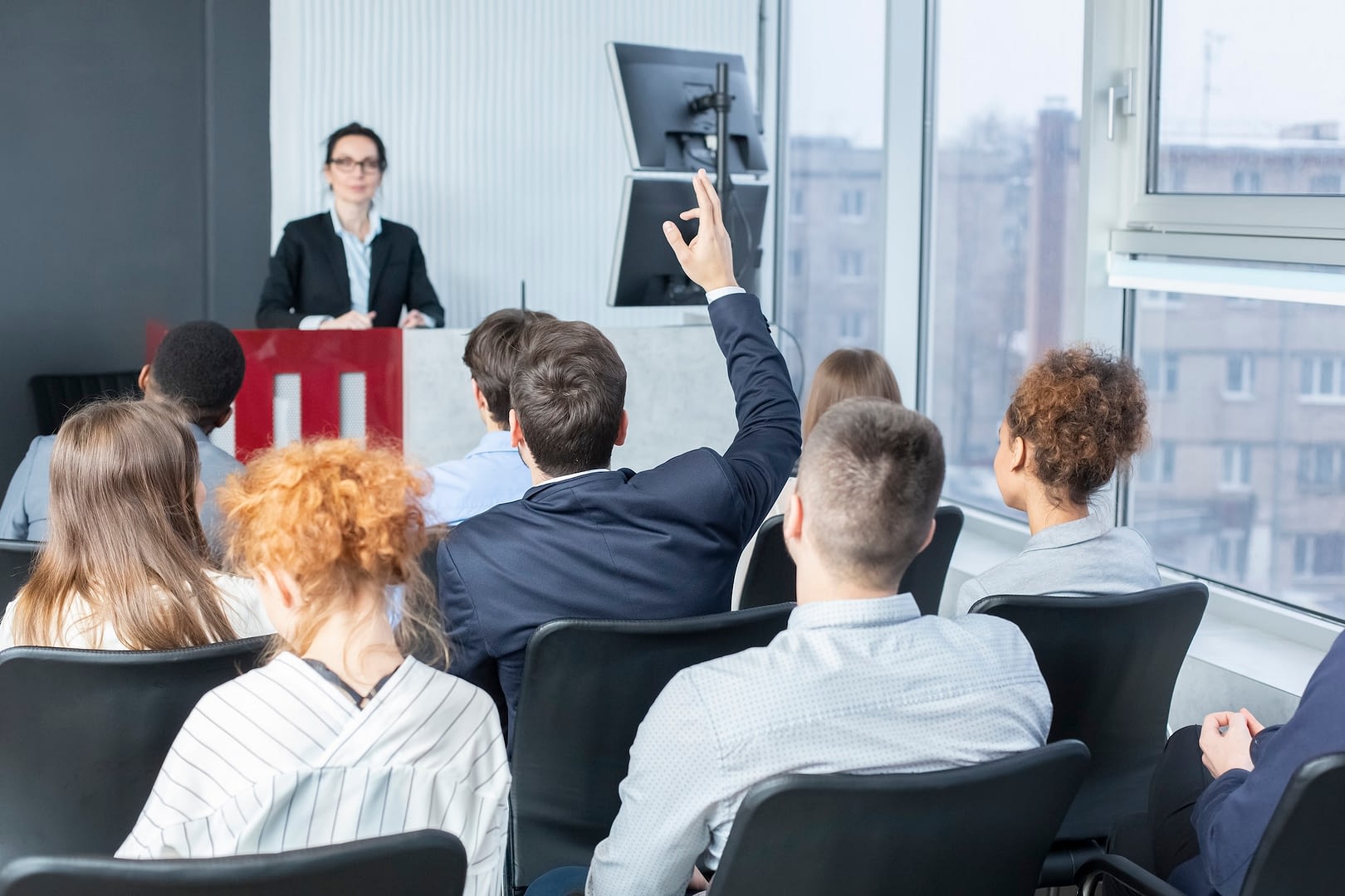 businessman raising hand at seminar having question to speaker