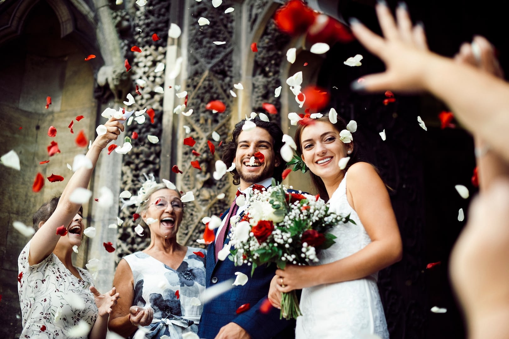 family throwing rose petals at the newly wed bride and groom