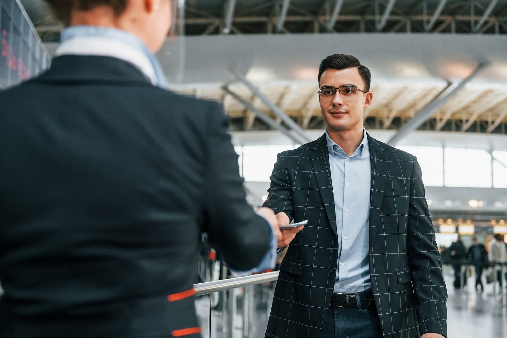 giving the documents young businessman in formal clothes is in the airport at daytime
