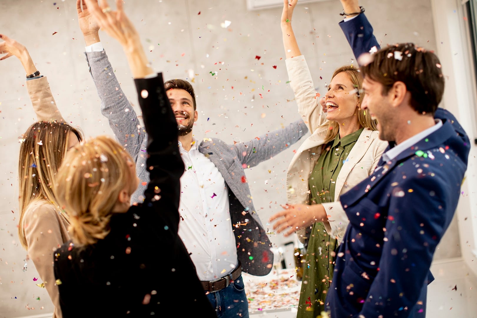 group of business people celebrating and toasting with confetti falling in the office