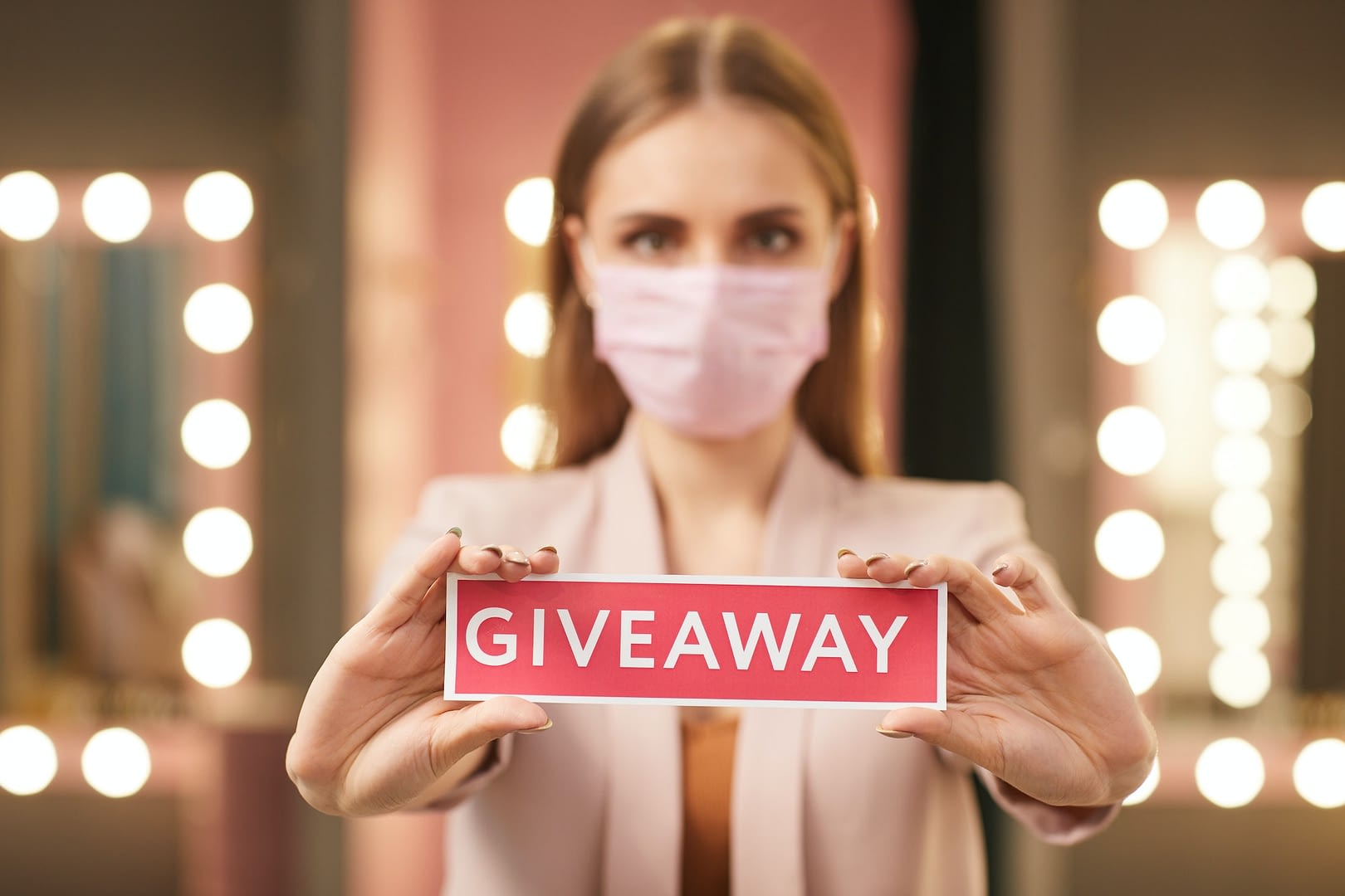 woman wearing face mask holding giveaway sign