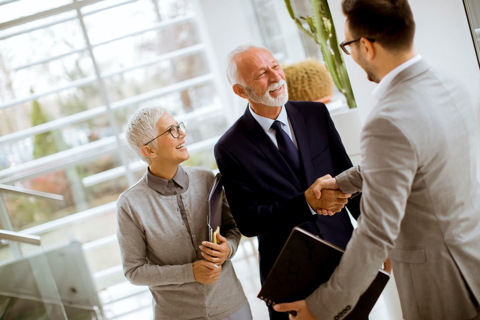 young businessman with senior clients standing in office