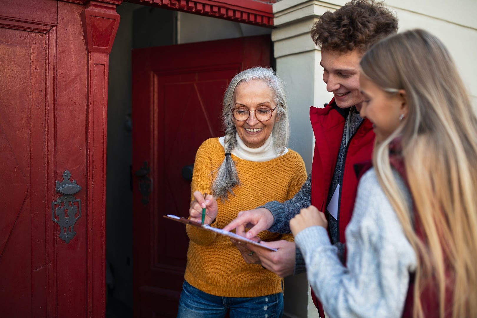 young door to door volunteers talking to senior woman and taking survey at her front door