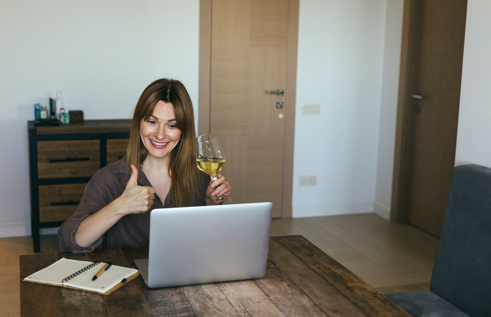 brunette woman is sitting at laptop chatting online with friends celebrating an important event