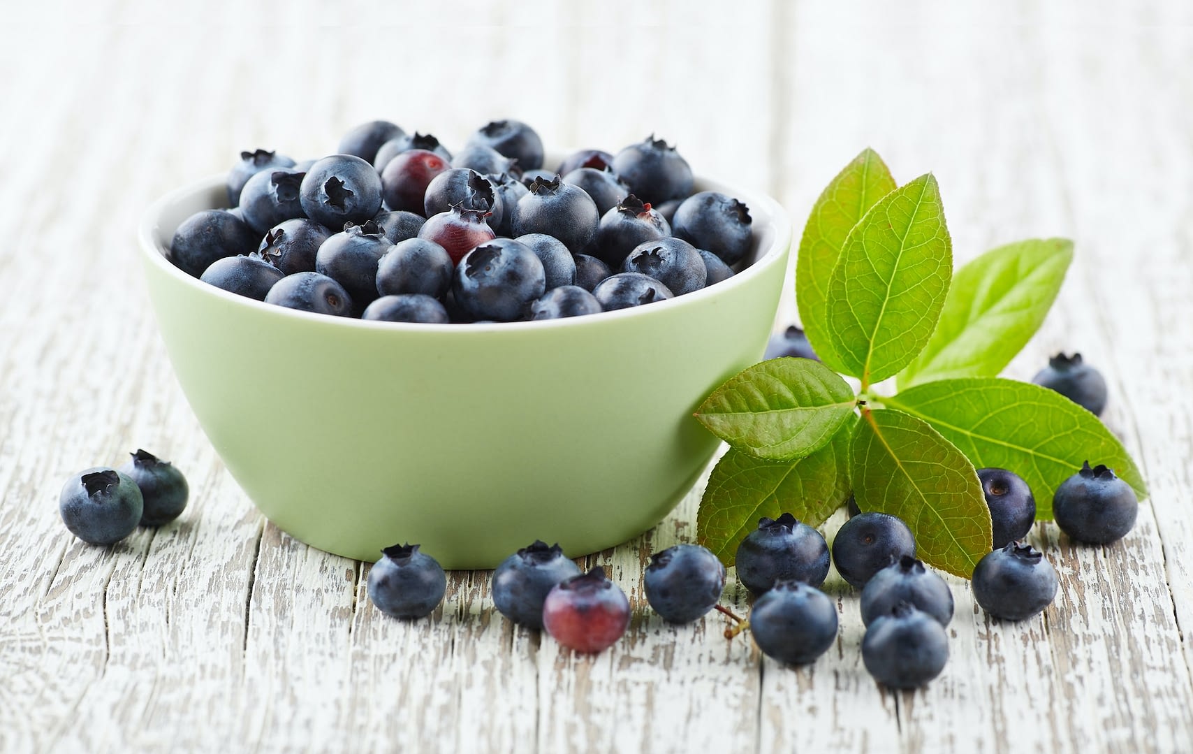 blueberry with leaves on a wooden white board