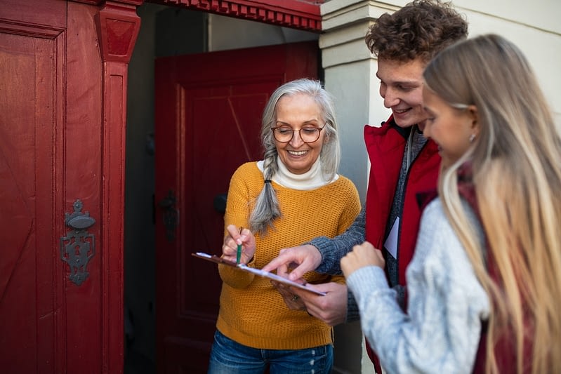 young door to door volunteers talking to senior woman and taking survey at her front door