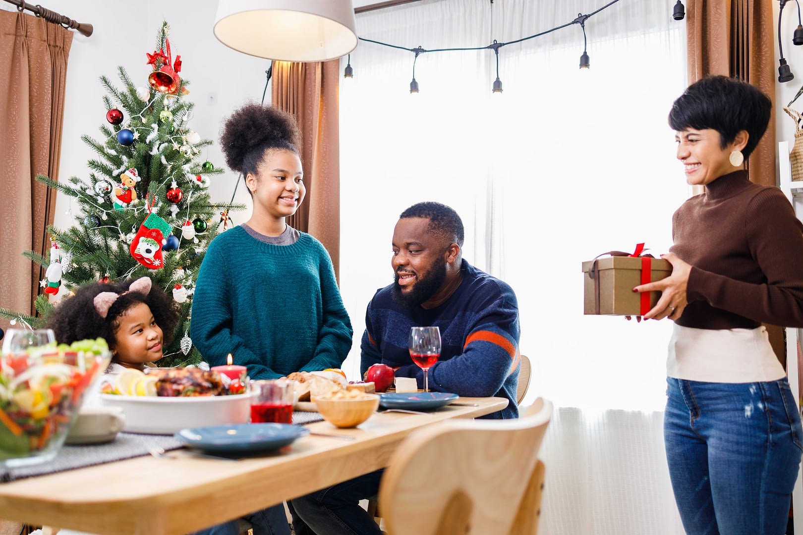 african american family surprised together with a gift on christmas day while dinner